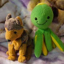 German shepard dog and green octopus plushies sitting side by side.